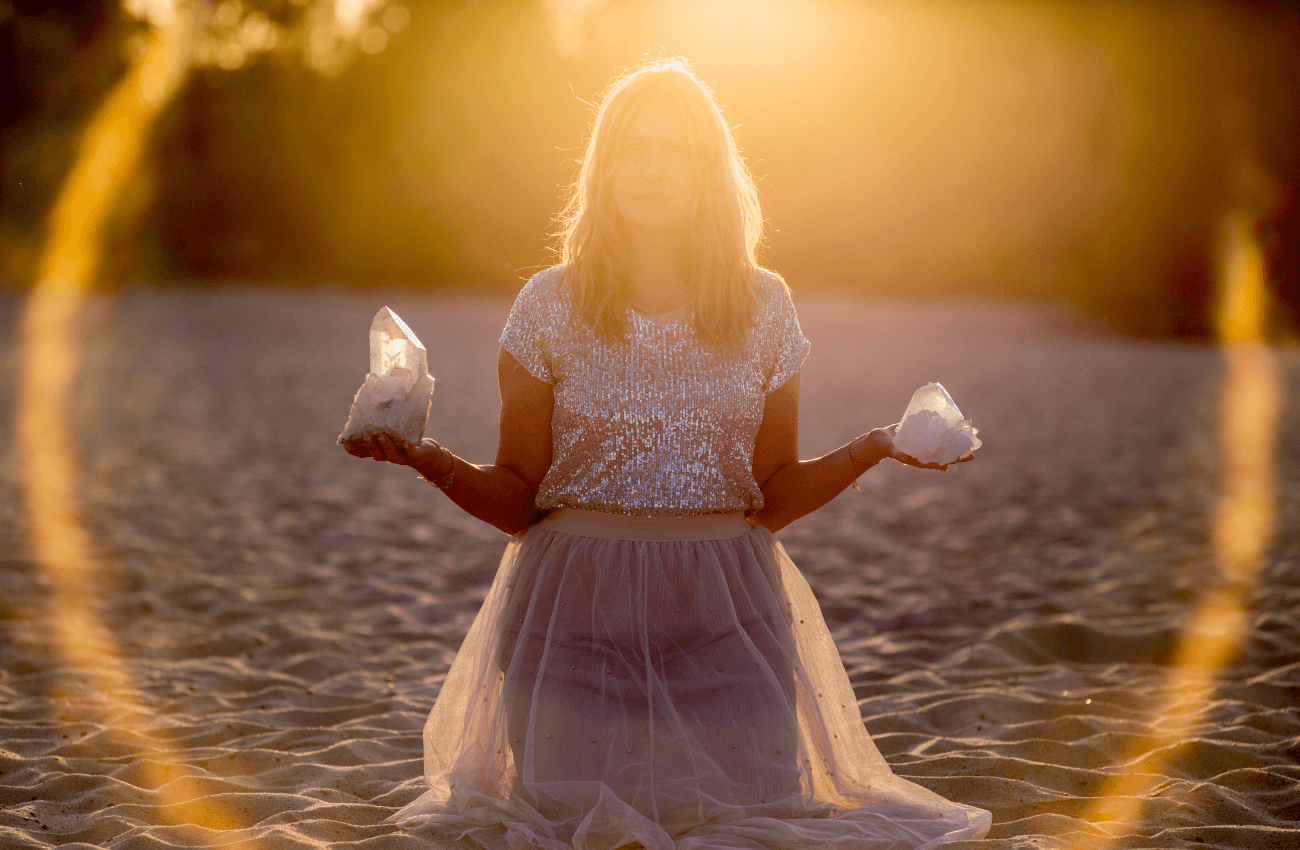Spiritual Woman on Sandy Beach Holding Crystals Practicing Crystal Healing